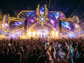 Large crowd at Celestial Sounds music festival facing a space-themed stage with lasers and pyrotechnics