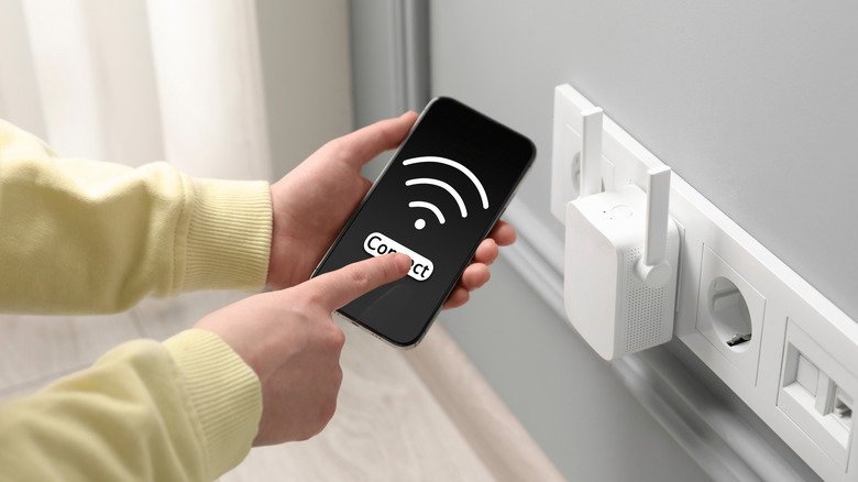 Turning a Retired Android Phone Into a Wi-Fi Extender: Does It Hold Up? 29 Wi-Fi extender plugged into an outlet and a person checking phone signal.