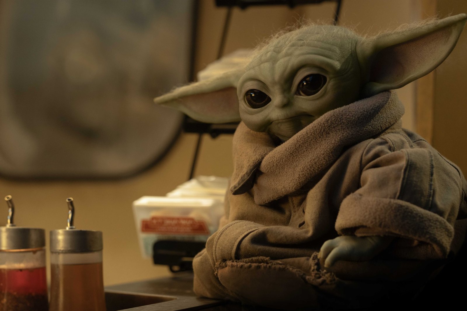 Grogu sits by some sauce dispensers in The Mandalorian and Grogu