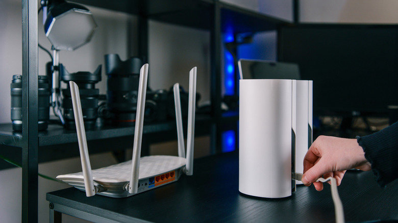 Should You Still Buy a Wi-Fi Extender in 2026? Here's the Catch 28 Someone setting up a mesh network, connecting an Ethernet cable in the back of a satellite node.