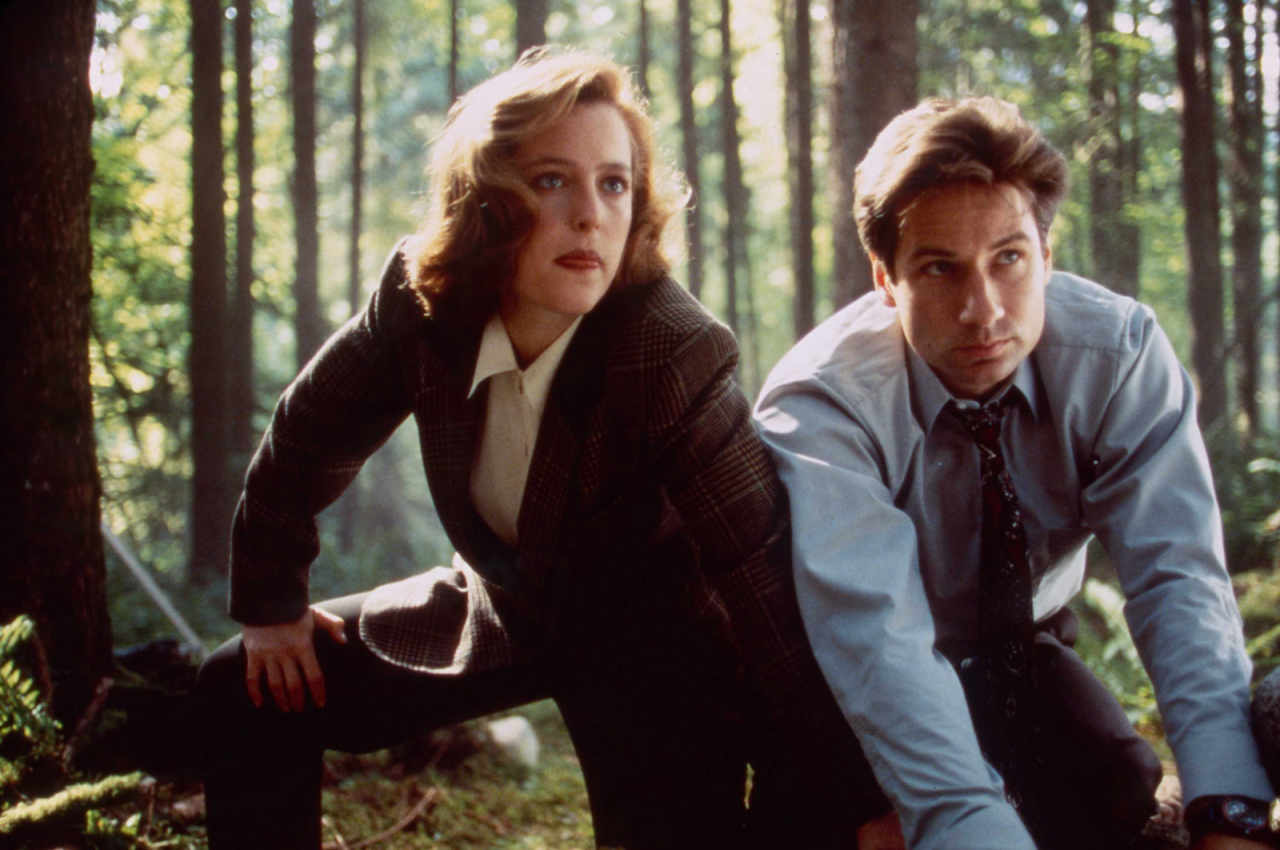 Mulder and Scully squatting in the woods in The X-Files