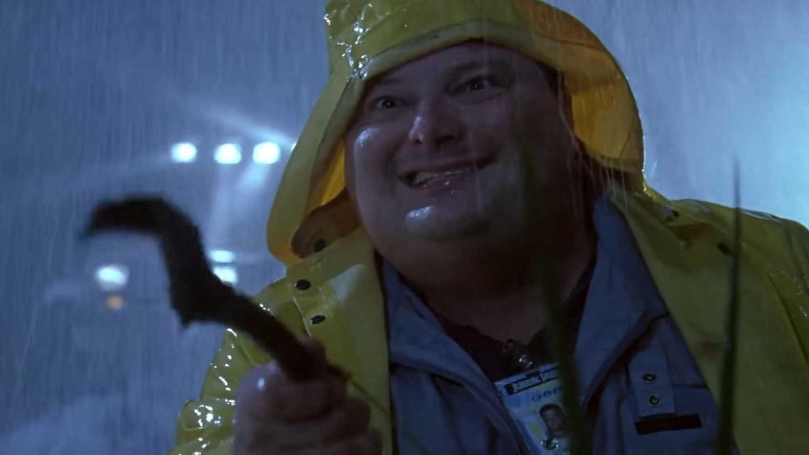 Dennis Nedry holding a stick trying to play with a dilophosaurus in Jurassic Park