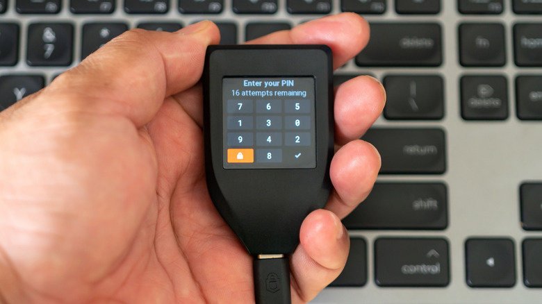 A Trezor hardware wallet in-hand with PIN input on-screen