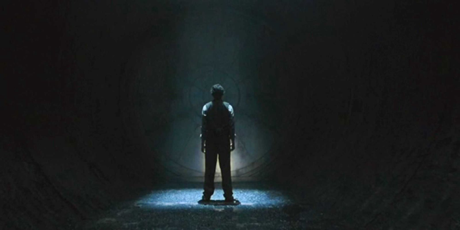 Avi Nash as Lukas Kyle standing in front of a mysterious vault door in Silo